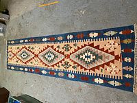 Top-down view of the entire kilim carpet runner laid on concrete floor showing colors and pattern in detail.