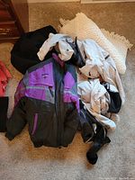Lot of four jackets and coats laid out on carpet floor.