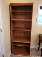 Full view of the oak and MDF bookshelf standing against a wall; shows overall design and condition with five shelves.