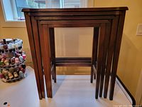 Four vintage wooden nesting tables nested together showing front view and leg design