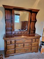 Full front view of the chest of drawers with mirror and shelves, showing carved detail, brass handles, and mirror etching.