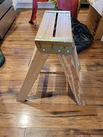 Side angle view of the wooden two-step ladder showing its structure and brass reinforced top step.