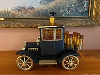 Full view of the black and gold vintage car-themed decanter set with glasses in place.