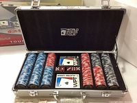 Opened metal carrying case showing poker chips in blue, red, white, and black colors, two decks of playing cards in WPT branded packaging.