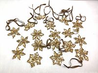 Multiple amber Swarovski crystal snowflake ornaments displayed together with brown hanging ribbons on a white surface.