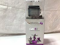 Photo of Safari 4K action camera inside its clear waterproof housing on top of product box with printed details.