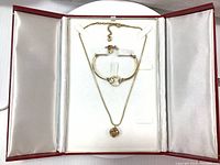 Open red Swarovski case with a gold-tone pendant necklace featuring an amber crystal and a matching gold-tone bracelet with a circular amber crystal.