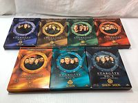 Seven Stargate SG-1 DVD box sets showing Seasons 1, 2, 3, 4, 6, 7, and 9 with artwork featuring main characters including Richard Dean Anderson.