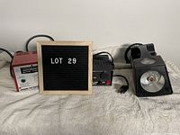 Photo showing all three items: MotorMaster battery charger (red box), black power supply converter, and handheld air compressor with light.
