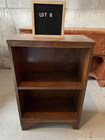 Front view of the small wooden bookshelf showing two shelves and worn finish.