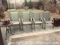 Side view of four metal mesh outdoor chairs arranged on a patio with some rust visible on frames.