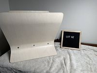 White washed wooden magazine rack viewed from an angle showing its curved, modern design and wear marks.