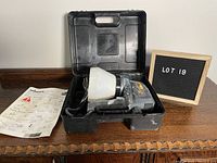 Wagner Power Painter paint sprayer in black carrying case with instruction manual next to it on wooden surface.