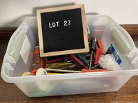 Clear plastic bin containing a large assortment of various used screwdrivers and tools, labeled 'LOT 27'.