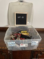 Plastic bin filled with assorted sheet metal tools showing the lot number 23 sign inside the bin.