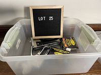 Plastic bin holding two metal staple guns and two boxes of staples, labeled as Lot 25