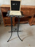 Full view of the vintage plant stand from the front, showing its height and three-legged wrought iron base.