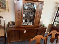 Front view of the wood buffet and hutch set with glass doors on the hutch top and wooden cabinets below.