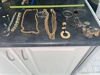 Full view of all costume jewelry items including necklaces, bracelets, and earrings spread out on a black surface.