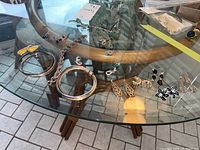 Overview of the jewelry lot on glass table showing bracelets, earrings, and necklace.
