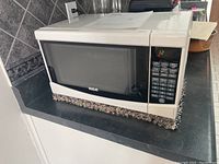 White RCA microwave, Model RMW733, on a kitchen counter with digital keypad and display.