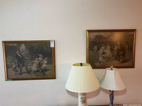 Two framed matching prints displayed on a wall above lamps. Both depict Victorian family scenes in outdoor settings.