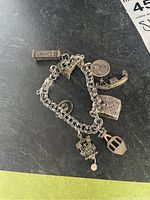 Full view of the sterling silver charm bracelet showing six unique travel-themed charms attached to a linked chain.