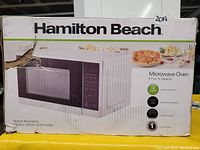 Box image showing Hamilton Beach Microwave Oven with 0.7 cu. ft. capacity, 700 watts power, multiple cooking functions and product dimensions