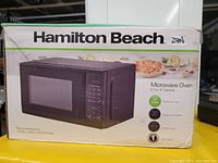 Photo of boxed Hamilton Beach microwave oven showing key features, power, and dimensions.