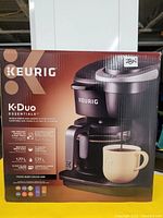Photo of the Keurig K-Duo Essentials coffee maker boxed with front view highlighting product features