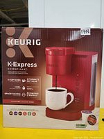 Boxed Keurig K-Express Essentials single serve coffee maker in red color with key features listed on the box.