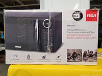 Photo of boxed RCA 0.9 cubic foot black microwave with 900 watt power, model RAWV953 Black. Box features image of microwave and key features such as child lock, electronic touchpad, and 0.9 cu ft capacity.