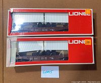 Two Lionel NP 9122 flat cars in original red/white Lionel boxes with clear windows showing the models inside. Boxes are visibly damaged.