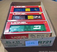 Three boxed Lionel box cars in a cardboard box with lot tag #16 visible.