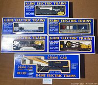Top view of all six original boxes showing train cars inside, blue and yellow K-Line Electric Trains packaging with clear windows.