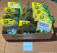 Lot of 11 John Deere Ertl tractors and Gator toys in original packaging viewed from top inside a box