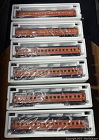 Six K-Line Heavyweights Southern Pacific Railroad model train cars in individual styrofoam trays showing orange and brown paint with window silhouette details.