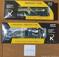 Two boxed K-LineO/O-27 scale freight cars showing original packaging with black and yellow design, one marked Freight Car and the other Operating Freight Car