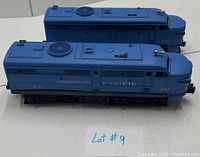 Side view of the Lionel 205 Missouri Pacific diesel locomotive and dummy car laid flat on white surface showing blue paint and markings.