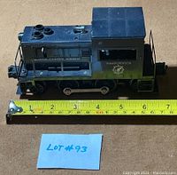 Side view of Lionel 41 Army Switcher showing scale next to measuring tape for size reference at about 6.5 inches.