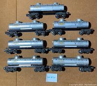 Top view of eight Lionel 6465 Sunoco 2-dome style tanker cars in silver with visible Sunoco logos and scratches.
