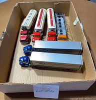 Top view of six diecast trucks in cardboard box showing various tractor trailer trucks and tankers.