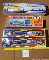 Top view of five vintage toy tanker trucks in original boxes on a brown surface; assortment includes Shell, Sunoco, Formula Shell brands