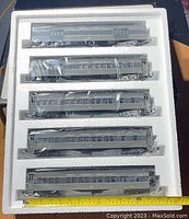 Top view showing all five grey passenger cars in original white styrofoam packaging and plastic wrap. Cars numbered and labeled 'New York Central' visible.