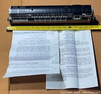 Locomotive next to measuring tape showing approximate length with instruction sheets below