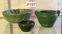 Three green pottery pieces: two smaller matt green Arts & Crafts pieces and a larger lighter green scalloped bowl.