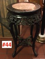 Full view of carved wooden pedestal stand with round marble inset top.