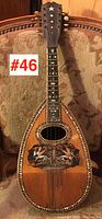 Full front view showing teardrop soundboard, oval sound hole, decorative lower bout inlay and mother-of-pearl fretboard motifs