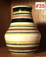 Full side view of the pottery vase showing the bulbous body and striped colorful pattern