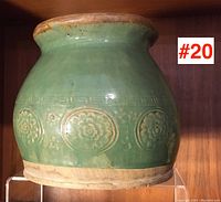 Full side view showing pot shape, green glaze, and embossed floral motifs with geometric band.